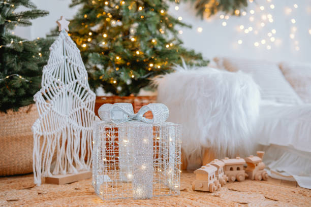 istock Sparkling gift box near decorative Christmas tree and cozy winter decor 2186543877