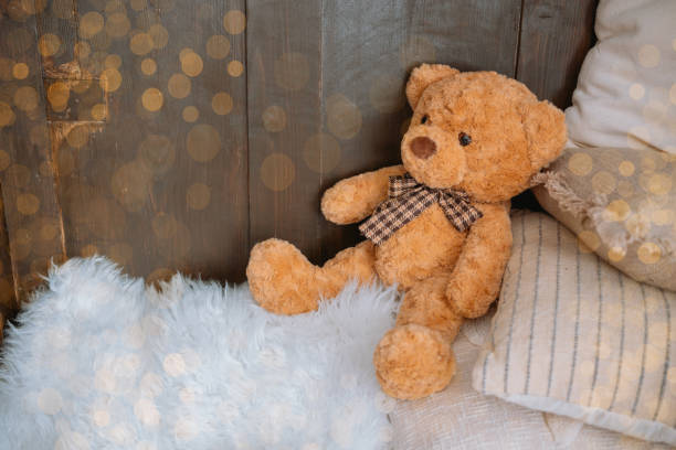 istock Cozy teddy bear sitting on soft pillows in a rustic room space 2186543885