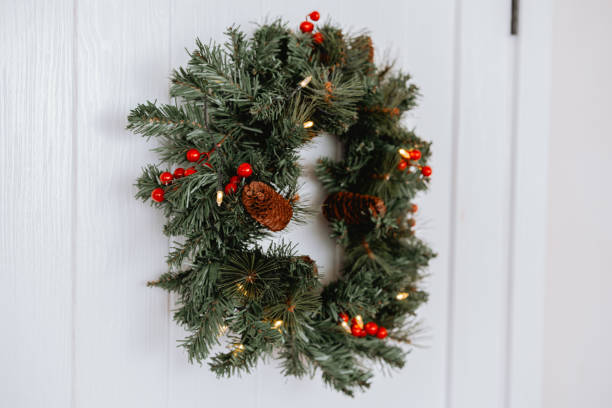 istock Decorative green wreath adorned with berries and pinecones hung on a door 2186544105