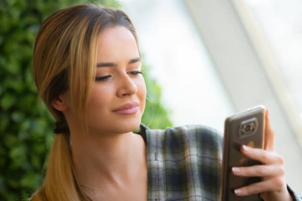 istock Young Blonde Entrepreneur Smiling While Checking Finance on Android Phone in Modern Coffee Shop 2186556890