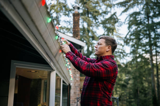 istock Man Putting Up Christmas Lights on Home Exterior 2186571969