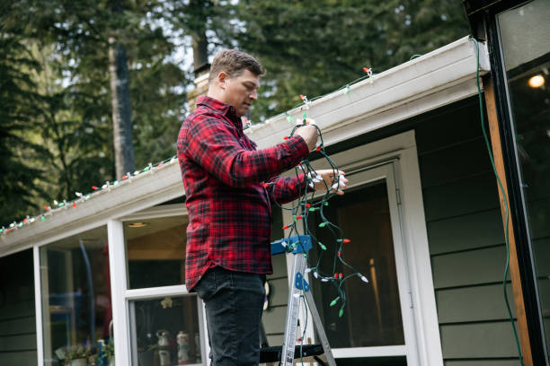 istock Man Putting Up Christmas Lights on Home Exterior 2186571970