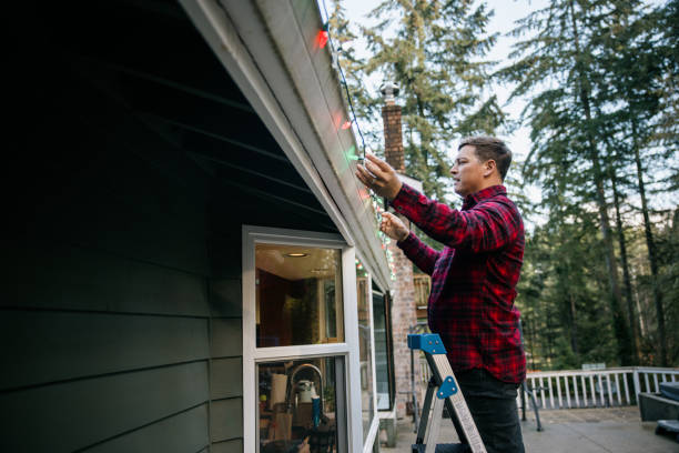 istock Man Putting Up Christmas Lights on Home Exterior 2186571993