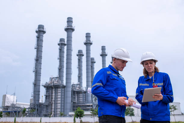 istock Engineers wearing safety gear, including hard hats examining survey a large blueprint tablet standing industrial facility gas or oil refinery engaged in a job requires high safety standards concept 2186572002