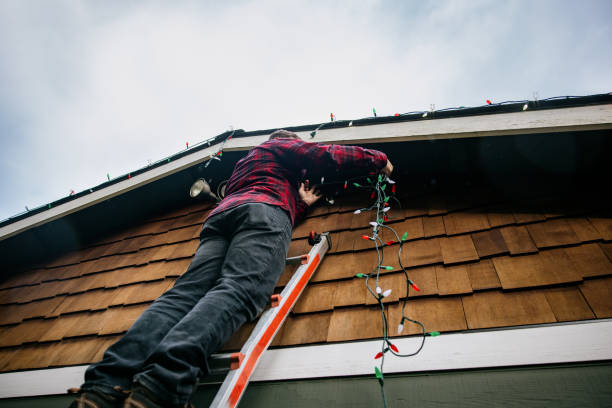 Man Putting Up Christmas Lights on Home Exterior