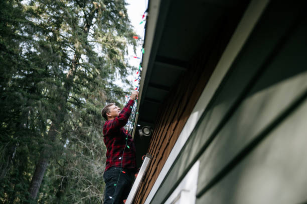 istock Man Putting Up Christmas Lights on Home Exterior 2186572018