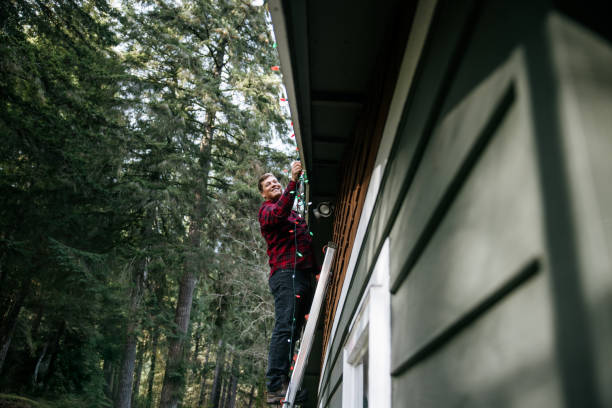 istock Man Putting Up Christmas Lights on Home Exterior 2186572020