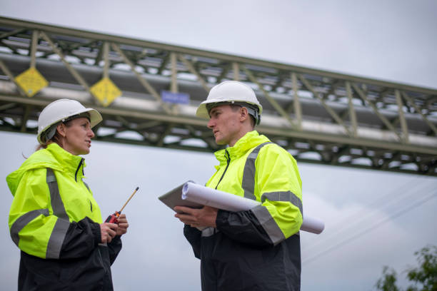 istock Engineers wearing safety gear, including hard hats examining survey a large blueprint tablet standing industrial facility gas or oil refinery engaged in a job requires high safety standards concept 2186572063
