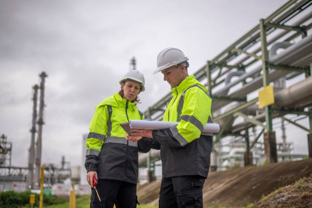 istock Engineers wearing safety gear, including hard hats examining survey a large blueprint tablet standing industrial facility gas or oil refinery engaged in a job requires high safety standards concept 2186572078