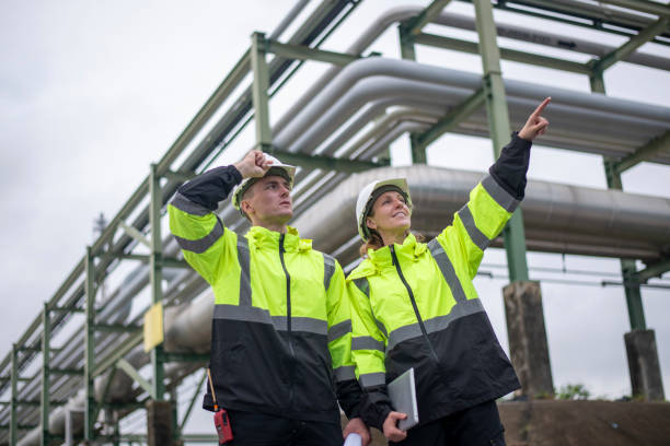 istock Engineers wearing safety gear, including hard hats examining survey a large blueprint tablet standing industrial facility gas or oil refinery engaged in a job requires high safety standards concept 2186572079