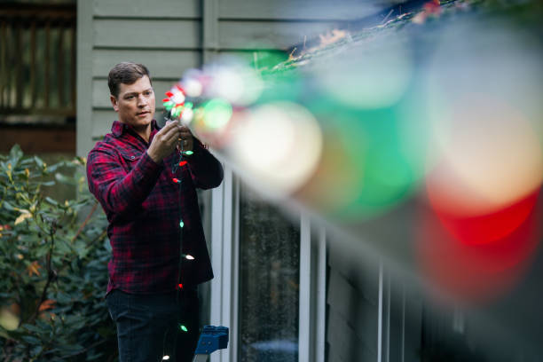 istock Man Putting Up Christmas Lights on Home Exterior 2186572094