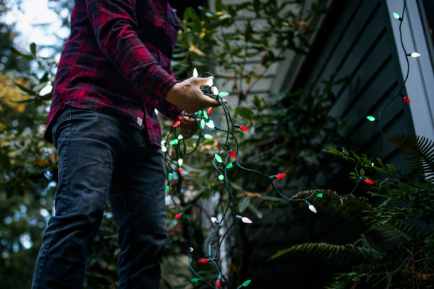 istock Man Putting Up Christmas Lights on Home Exterior 2186572108