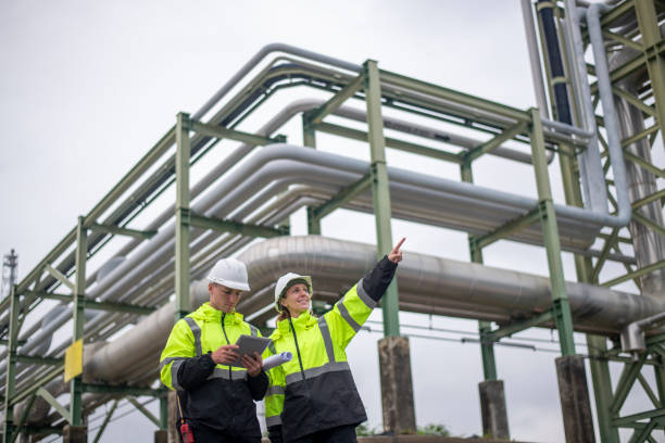 istock Engineers wearing safety gear, including hard hats examining survey a large blueprint tablet standing industrial facility gas or oil refinery engaged in a job requires high safety standards concept 2186572119