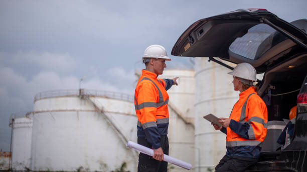 istock Engineers wearing safety gear, including hard hats examining survey a large blueprint tablet standing industrial facility gas or oil refinery engaged in a job requires high safety standards concept 2186572123