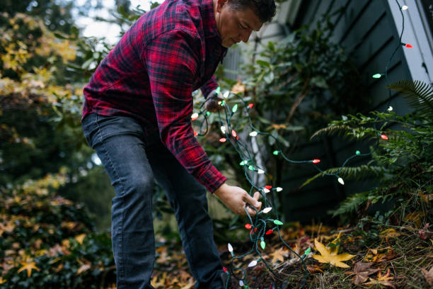 istock Man Putting Up Christmas Lights on Home Exterior 2186572149