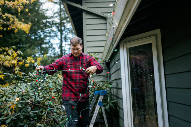 istock Man Putting Up Christmas Lights on Home Exterior 2186572151