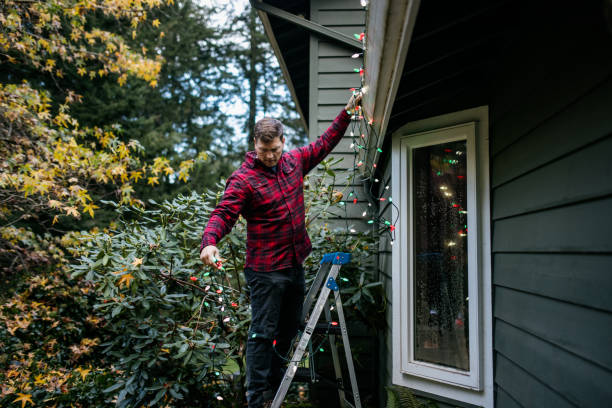 Man Putting Up Christmas Lights on Home Exterior