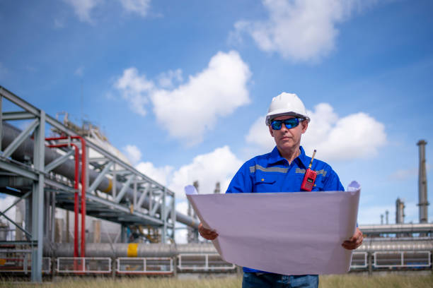istock Engineers wearing safety gear, including hard hats examining survey a large blueprint tablet standing industrial facility gas or oil refinery engaged in a job requires high safety standards concept 2186572434
