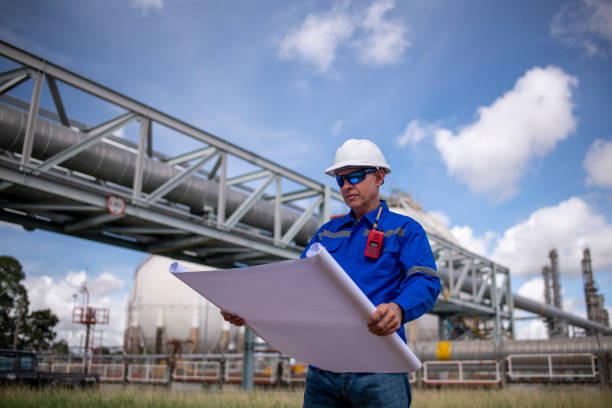 istock Engineers wearing safety gear, including hard hats examining survey a large blueprint tablet standing industrial facility gas or oil refinery engaged in a job requires high safety standards concept 2186572439