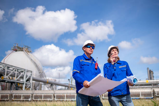 istock Engineers wearing safety gear, including hard hats examining survey a large blueprint tablet standing industrial facility gas or oil refinery engaged in a job requires high safety standards concept 2186572444