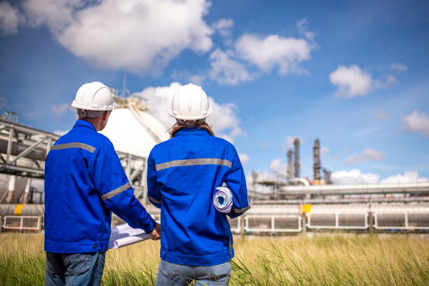 istock Engineers wearing safety gear, including hard hats examining survey a large blueprint tablet standing industrial facility gas or oil refinery engaged in a job requires high safety standards concept 2186572446