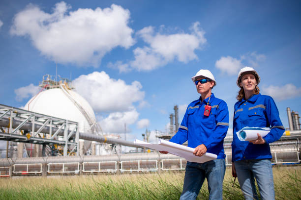 istock Engineers wearing safety gear, including hard hats examining survey a large blueprint tablet standing industrial facility gas or oil refinery engaged in a job requires high safety standards concept 2186572448