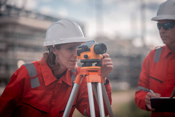 istock Surveyor engineers team wearing safety uniform and blueprint checking inspection by theodolite telescope to measurement level position railway construction site is industry transportation concept. 2186572570