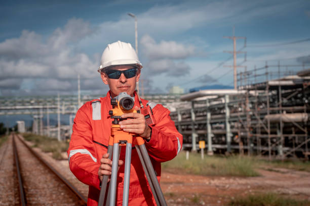 Surveyor engineers team wearing safety uniform and blueprint checking inspection by theodolite telescope to measurement level position railway construction site is industry transportation concept.