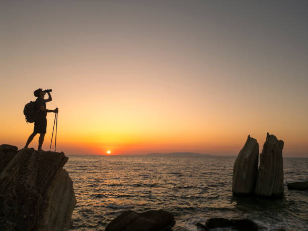 istock Hiker drinking water and admiring sunset over the sea 2186575133