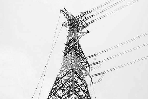 Black and white photo, Silhouette of high voltage tower and electric line with the sky background.