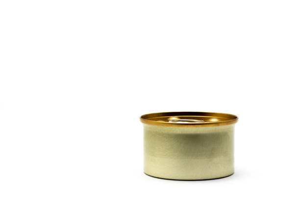 Can of food is sitting on a white background. The can is made of metal and has a gold rim. Concept of simplicity and minimalism, with the focus on the can and its surroundings.