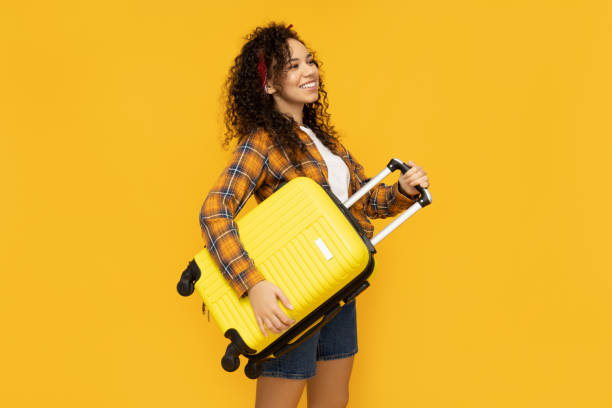 istock Young woman with suitcase on yellow background 2186580899