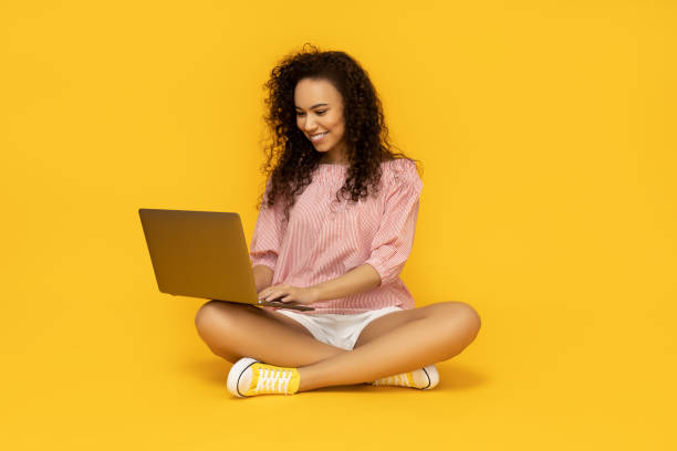 istock Young woman with laptop on yellow background 2186581442