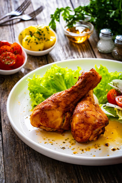 istock Barbecued chicken drumsticks with fresh vegetables on wooden table 2186581725