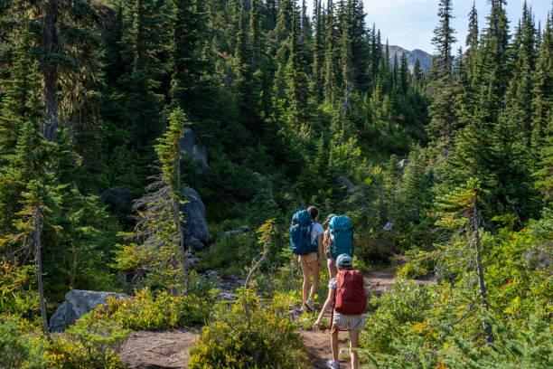 istock Mother and daughters backpack on mountain trail 2186582876