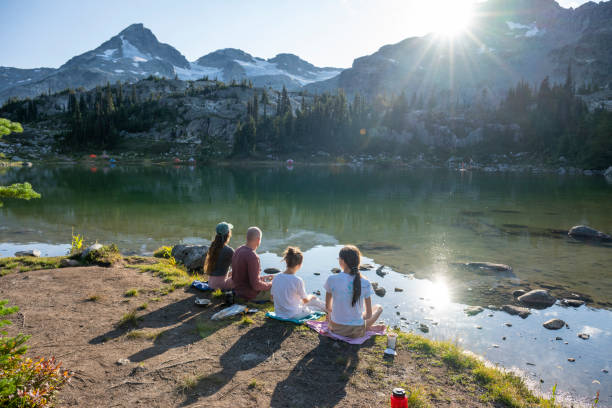 istock Family relaxes on lakeshore below glaciated mountains 2186582883
