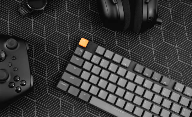 gamer work space concept, top view a gaming gear, mouse, keyboard, joystick, headset, mobile joystick, in ear headphone and mouse pad on black table background.