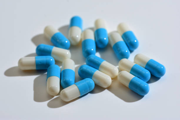 Vibrant blue and white capsules are scattered across a surface, displaying a mixture of sizes and designs. The smooth surfaces reflect light, creating an intriguing visual of color contrasts and textures in a close-up view.