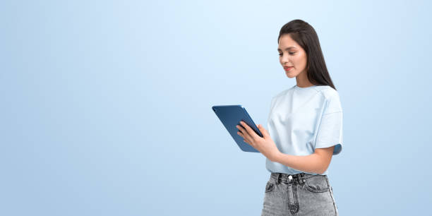 istock Smiling woman looking at tablet in hands, copy space background 2186591260