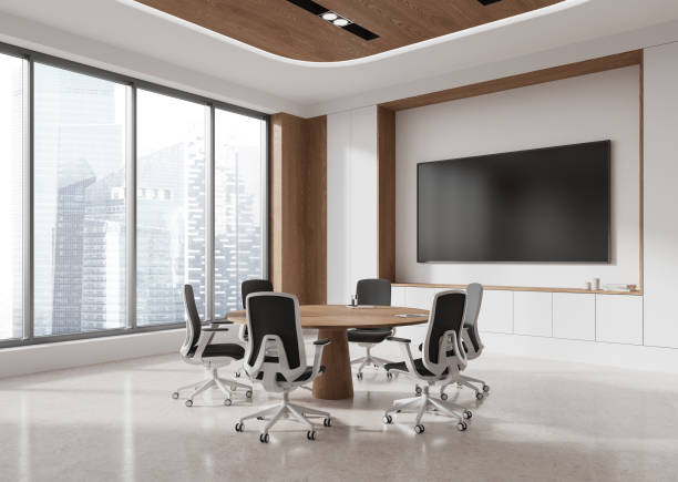 istock Stylish office interior with negotiation table and chairs, tv display and window 2186593242