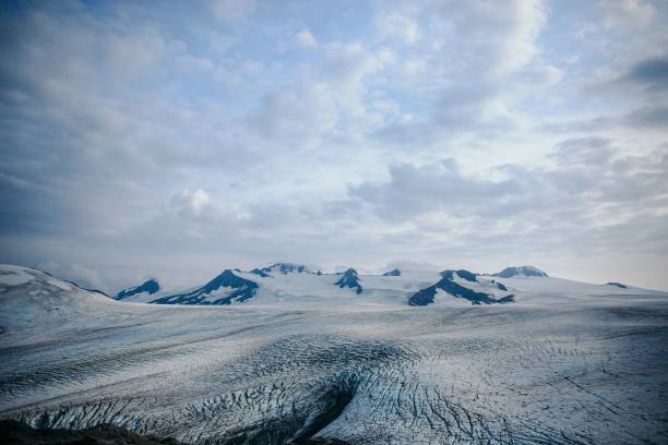 A breathtaking view of a glacier with snow-capped peaks under a cloudy sky, showcasing the beauty of nature.