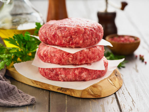 istock Stack of fresh raw burger patty or ground beef meat burger steak cutlets on dark wooden background. 2186600607