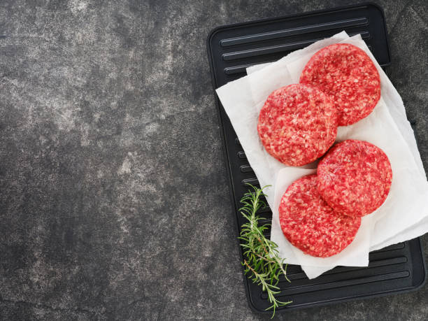 istock Four fresh raw burger patty or ground beef meat burger steak cutlets on dark wooden background. Top view. 2186600708