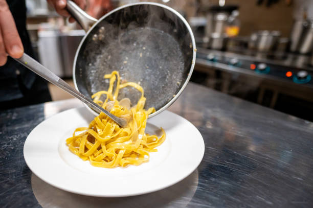 istock A chef serves freshly cooked fettuccine pasta, steaming and plated elegantly, showcasing culinary expertise in a professional kitchen environment. 2186604334