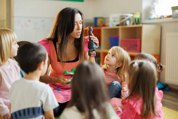 istock Teacher holds toy animals while telling a story to small children 2186604366
