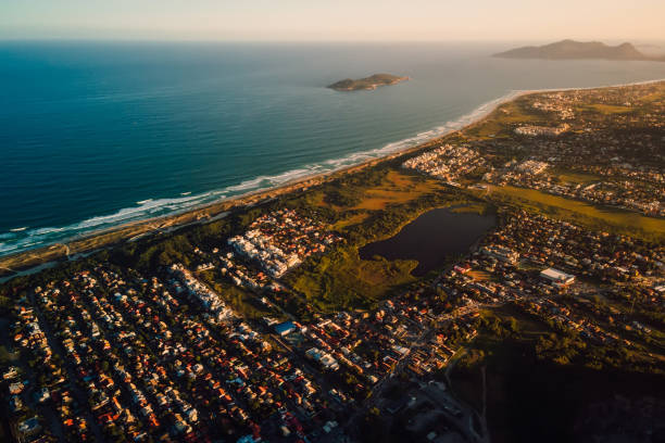 Coastline with ocean and town with sunset tones in Florianopolis, above view
