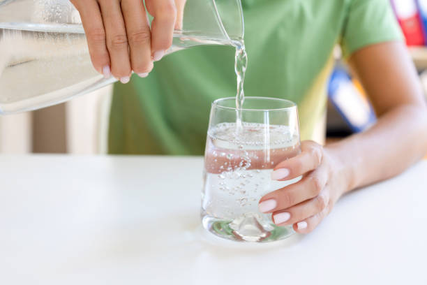 istock Female pouring water from jug into glass 2186630832