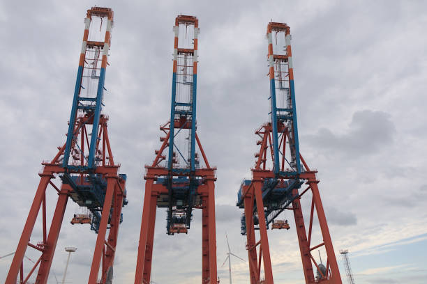 Hamburg, Germany - 09 16 2024: Towering gantry cranes in red and blue against the sky.