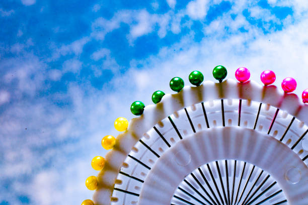 A scattered collection of colorful sewing pins with round heads on a white background. The pins feature a variety of vibrant colors including red, green, blue, yellow, pink, and purple, making them visually appealing and perfect for sewing, quilting, and craft projects. The image captures the pins in a random arrangement, highlighting their sharp metallic needles and glossy heads. Ideal for use in articles, blogs, and tutorials related to sewing, crafting, and DIY projects.