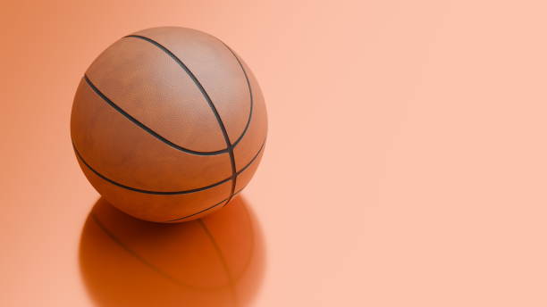 istock singular brown basketball lies on a polished orange surface, its textured pattern visible, creating an inviting atmosphere for enthusiasts of the game to engage 2186633087